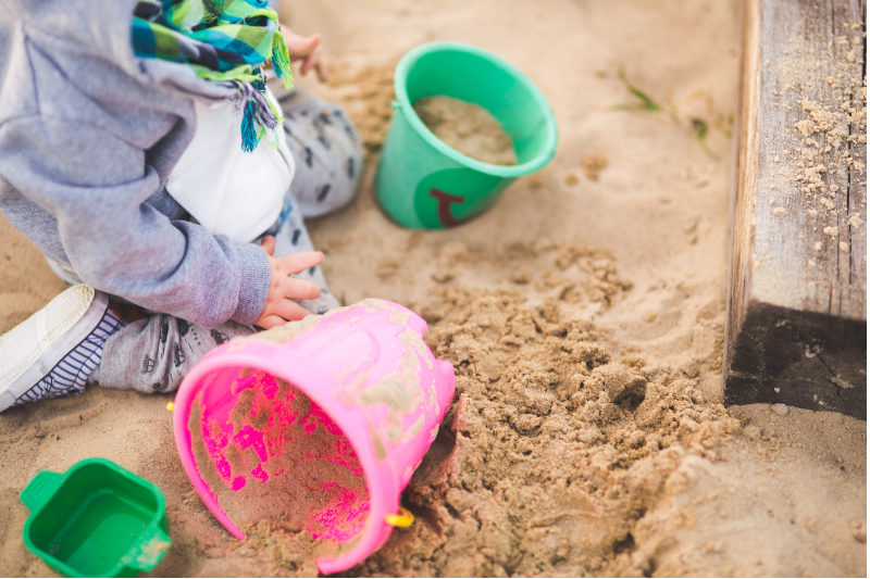 Spielende Kinder sollten im Sandkasten vor der Sonne geschützt werden.