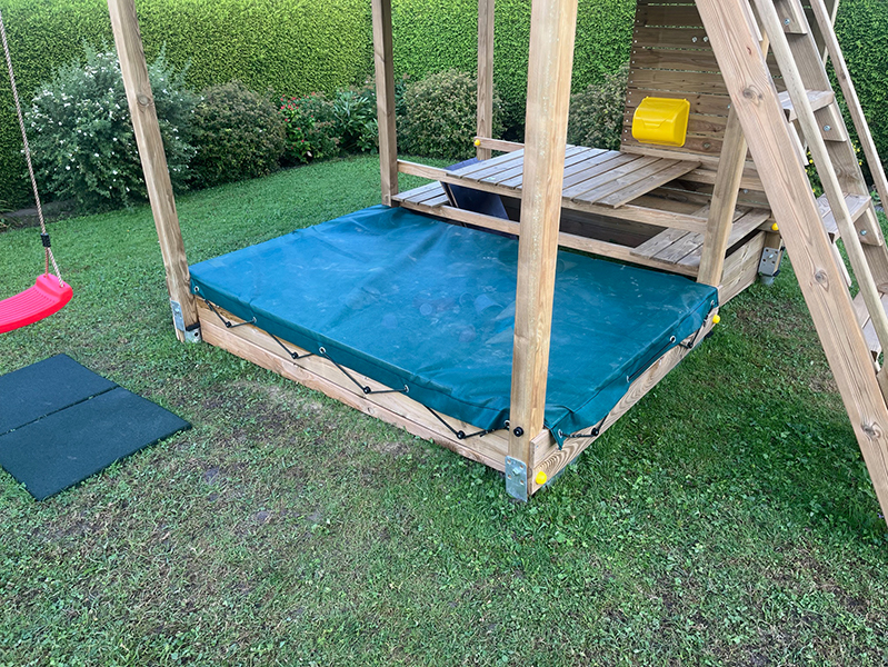Abgedeckter Sandkasten mit einer gummierten Sandkastenabdeckung mit Aussparungen